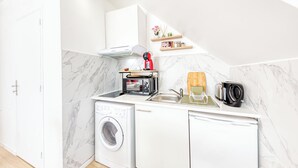 Une cuisine compacte équipée d’un lave-linge, d’un grille-pain et d’une machine à café.