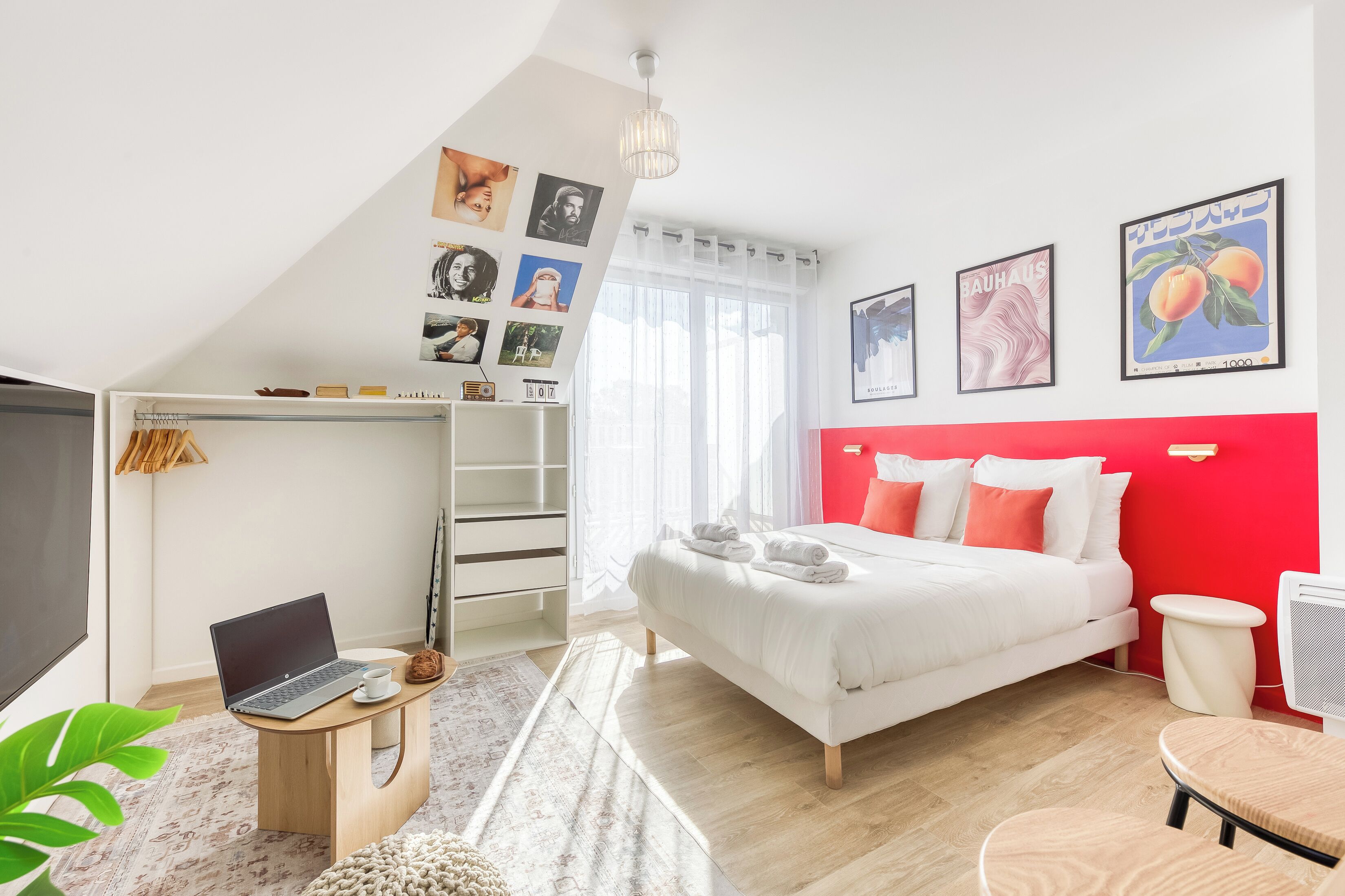 Une chambre à coucher avec un lit, un bureau avec un ordinateur portable, une télévision et une armoire.