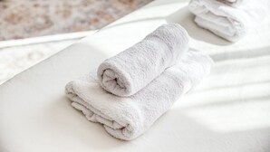 Une serviette blanche, soigneusement pliée, posée sur une surface blanche, probablement dans une chambre d’hôtel.