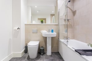 Ein modernes Badezimmer mit Toilette, Waschbecken und Badewanne.