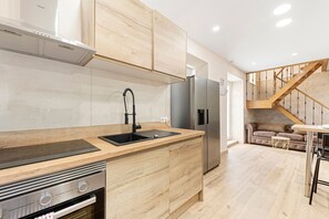 A modern kitchen with wooden cabinets, stainless steel appliances, and a built-in oven. - Cruz Verde 10 Suites Malaga (Malaga)