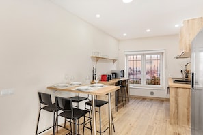 A modern kitchen with a dining area, wooden cabinets, and a window with a view. - Cruz Verde 10 Suites Malaga (Malaga)