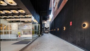 A narrow indoor corridor with a modern design, featuring a glass storefront on the left and a dark wall on the right. - MK Colombo (Colombo)