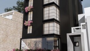 Un bâtiment moderne à la façade noire, doté de nombreuses fenêtres et agrémenté de fleurs roses sur les balcons.