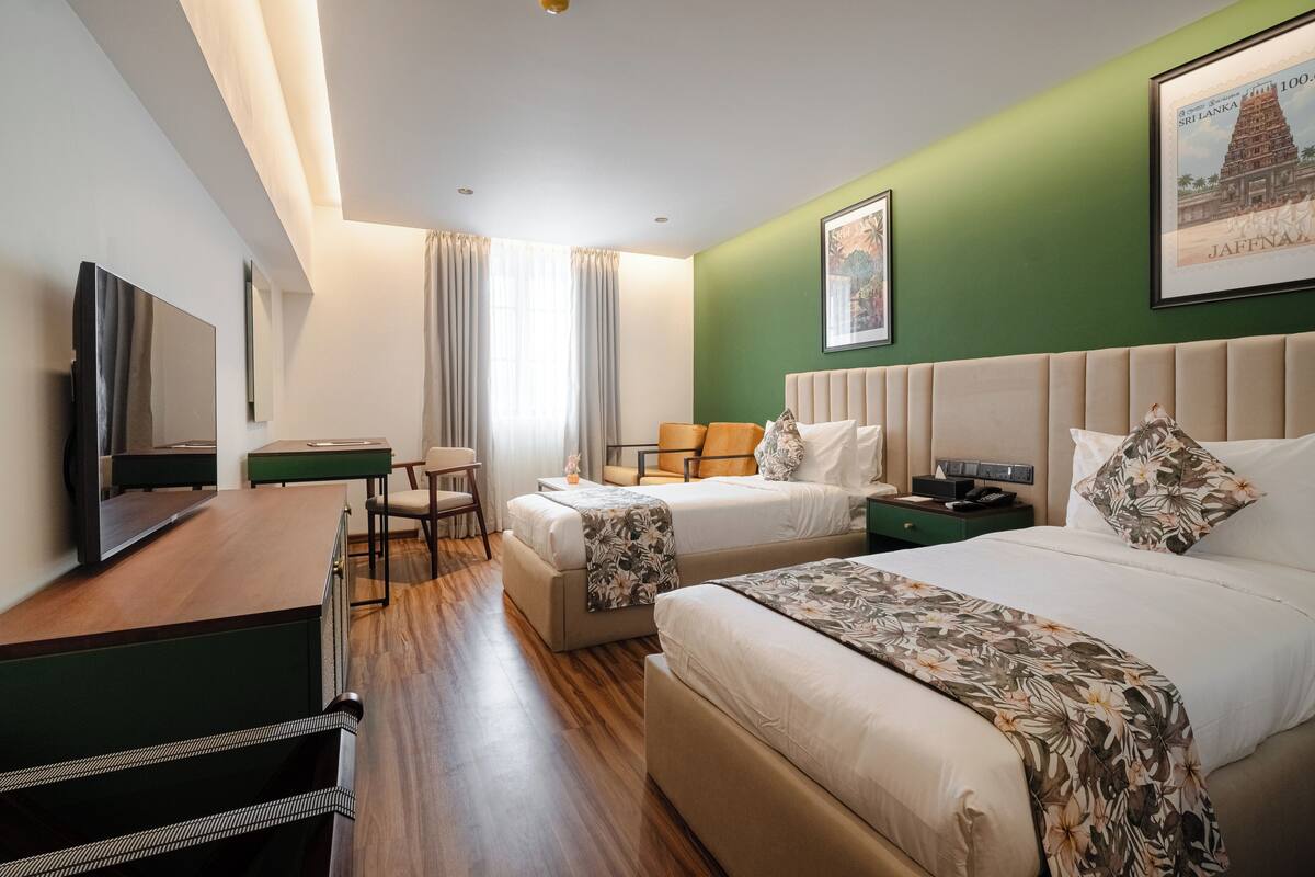 A hotel room with a bed, a desk, a chair, and a television.