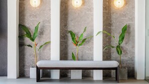 Un banc placé devant trois panneaux muraux en forme d’arc, ornés de lignes verticales, et des lampes fixées au mur.