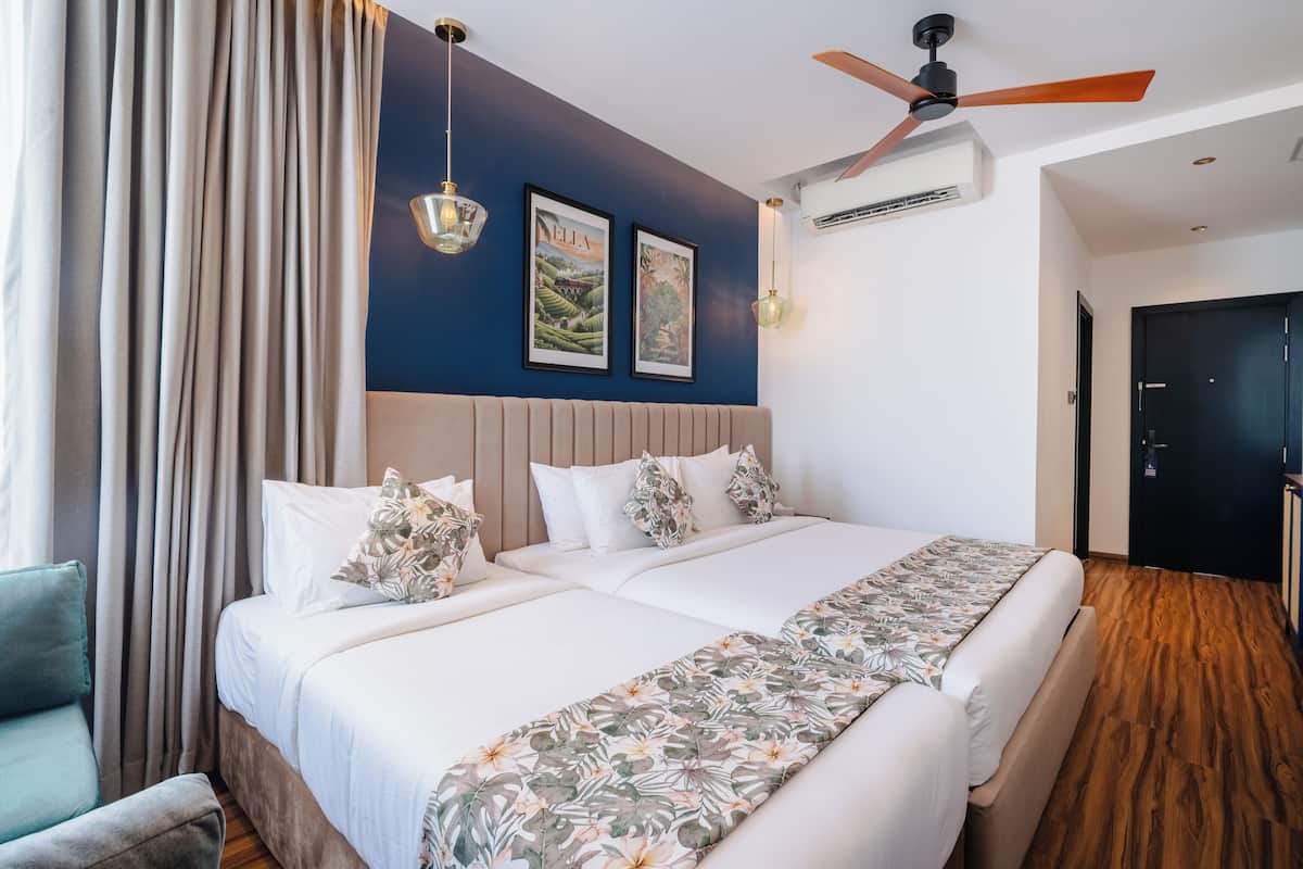 A double bed with a floral bedspread, a ceiling fan, and two wall-mounted light fixtures.
