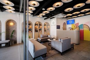 En modern entréhall med sittplatser, en receptionsdisk och en tv-skärm.