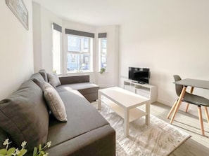 Un salon moderne comprenant un canapé, une table basse, un téléviseur et un coin repas.