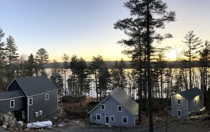 A residential area with houses near a body of water, surrounded by trees. - Impressive Cottage with Fire Pit and Lake Access in Orland, Maine (Orland)