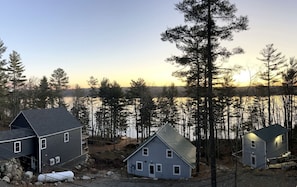 A residential area with houses near a body of water, surrounded by trees. - Impressive Cottage with Fire Pit and Lake Access in Orland, Maine (Orland)