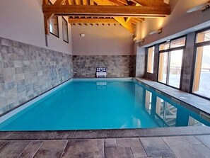 Ein Innenpool mit Steinwänden und Holzbalken.
