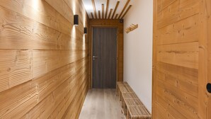 A wooden hallway with a bench, a door, and wall-mounted lighting fixtures. - Modern apartment in Monêtier, near the village (Le Monêtier-les-Bains)