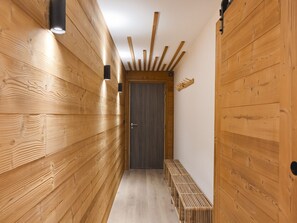 A wooden hallway with a bench, a door, and wall-mounted lighting fixtures. - Modern apartment in Monêtier, near the village (Le Monêtier-les-Bains)