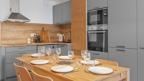 A modern kitchen with grey cabinets, a wooden dining table set for six, and a Bosch oven. - Modern apartment in Monêtier, near the village (Le Monêtier-les-Bains)