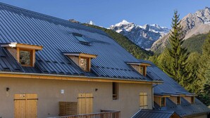 A chalet with a sloped roof, wooden balconies, and a mountain backdrop. - Modern apartment in Monêtier, near the village (Le Monêtier-les-Bains)