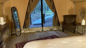 Une tente équipée d’un lit, d’une chaise, d’une table et offrant une vue sur l’extérieur.