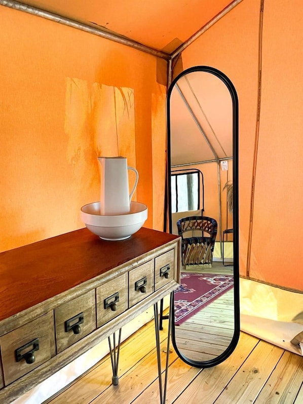 A room with a wooden dresser, a white vase, and a mirror reflecting a tent-like structure. - Luxuriously Romantic Safari Tent in Livingston, Texas (Livingston)
