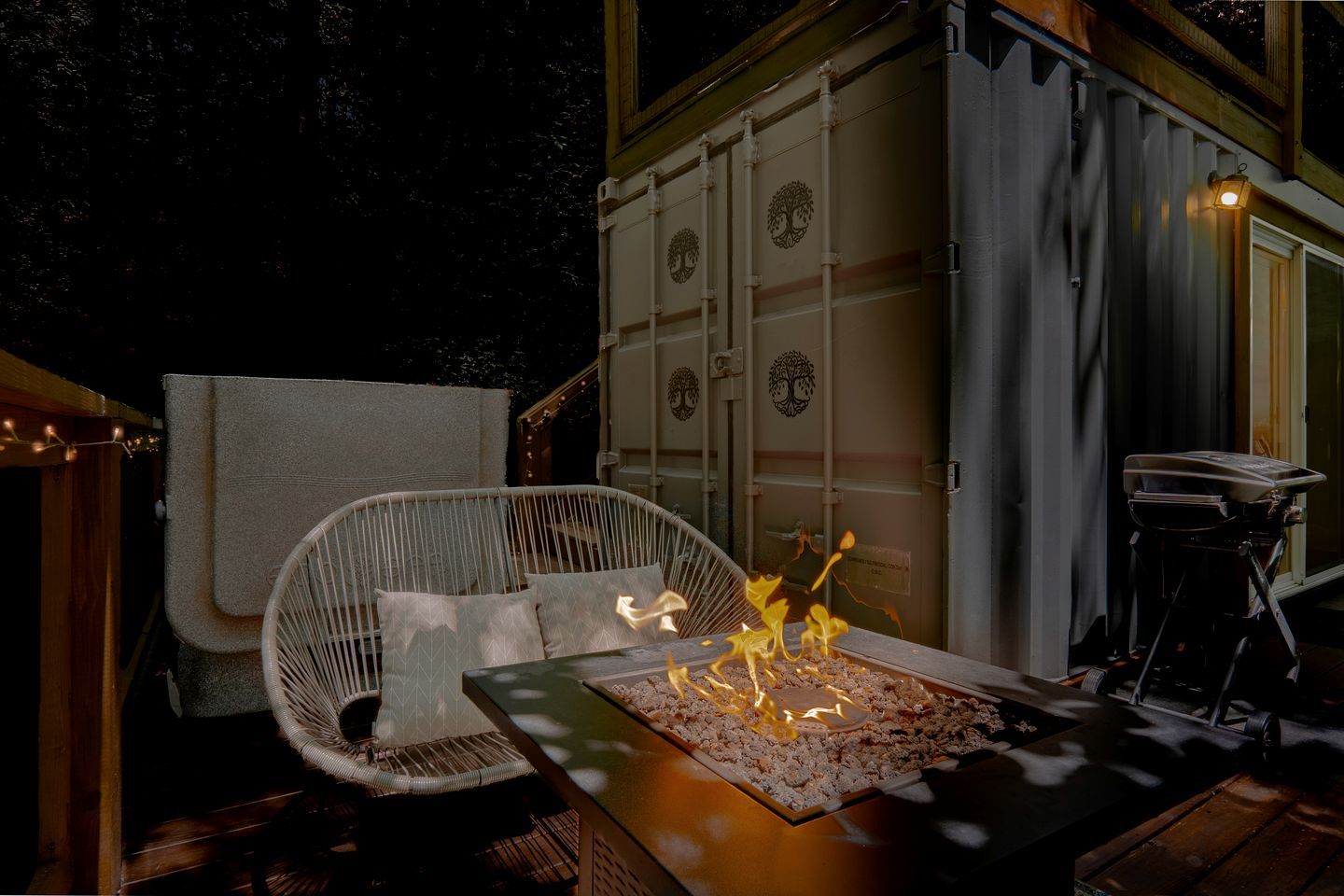 Un espacio exterior acogedor con una chimenea, una silla de mimbre y una parrilla.