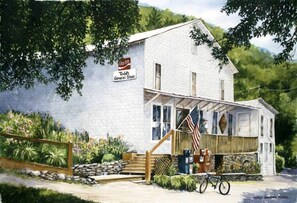 A white building with a Coca-Cola sign, a porch, and a bicycle. - Elevated Getaway: Exclusive Tiny House with Hot Tub and Deck Views in Todd, NC (Todd)