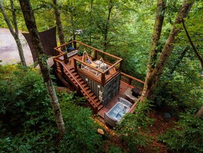 A wooden cabin with a hot tub, surrounded by dense forest. - Elevated Getaway: Exclusive Tiny House with Hot Tub and Deck Views in Todd, NC (Todd)