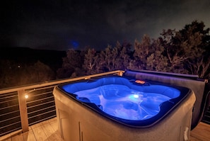 A hot tub on an outdoor deck with a view of trees and hills in the background. - Rest and Recharge at this Wonderful Glamping Destination in Burnet, Texas (Burnet)