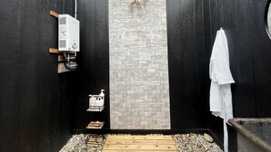 Une salle de bain avec un mur en briques noir et blanc, un plafond en bois, une serviette blanche suspendue et un espace douche.