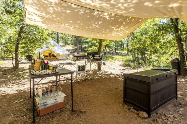 Un espace de camping aménagé avec une tente, des tables, un barbecue et une table de billard.