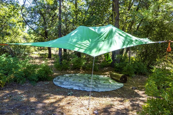 A tent set up in a forested area with a tarp on the ground.