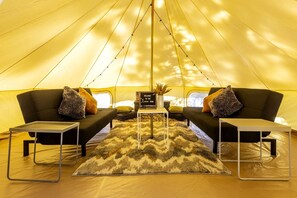 A tent with two sofas, a small table, and a rug.
