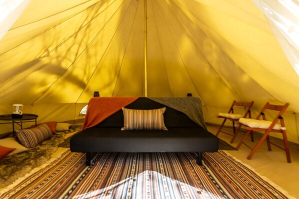 A tent with a bed, a table, and chairs inside.
