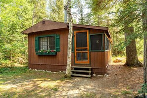 A small wooden cabin with a door, windows, and a chimney, surrounded by trees. - Charming Pet-Friendly Cabin in Ely, Ideal for Getaways to Nature in Minnesota (Ely)
