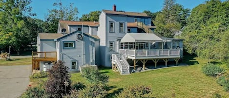 A large two-story house with a covered deck and a small boat dock.