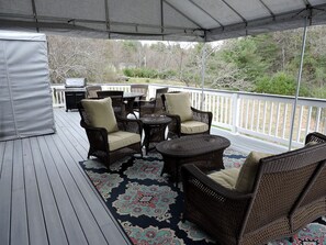 A covered outdoor deck with wicker furniture, a small table, and a laptop.