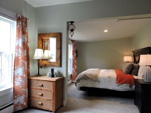 A bedroom with a bed, dresser, lamp, and a mirror.