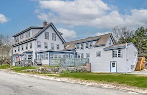 A large, two-story house with a porch and a small attached building. - Cabin Retreat for Nature and City Exploration near Sebago Lake State Park, ME (Casco)