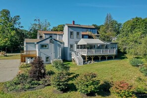 Une grande maison à deux étages, dotée d’une terrasse couverte et d’un petit quai pour bateaux.