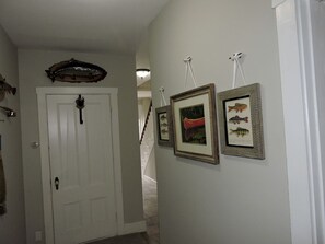 A hallway with a white door, framed fish pictures, and a fish-shaped decoration on the wall. - Cabin Retreat for Nature and City Exploration near Sebago Lake State Park, ME (Casco)