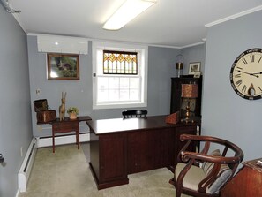 A room with a desk, a chair, a clock, a window with stained glass, and a radiator. - Cabin Retreat for Nature and City Exploration near Sebago Lake State Park, ME (Casco)