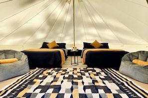 A tent-style room with two beds, a patterned rug, and two bean bag chairs.