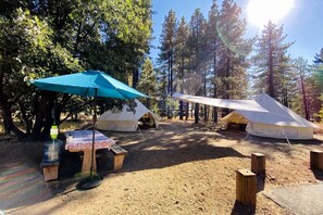 Un camping con tiendas de campaña, una mesa de picnic y un dispensador de agua.