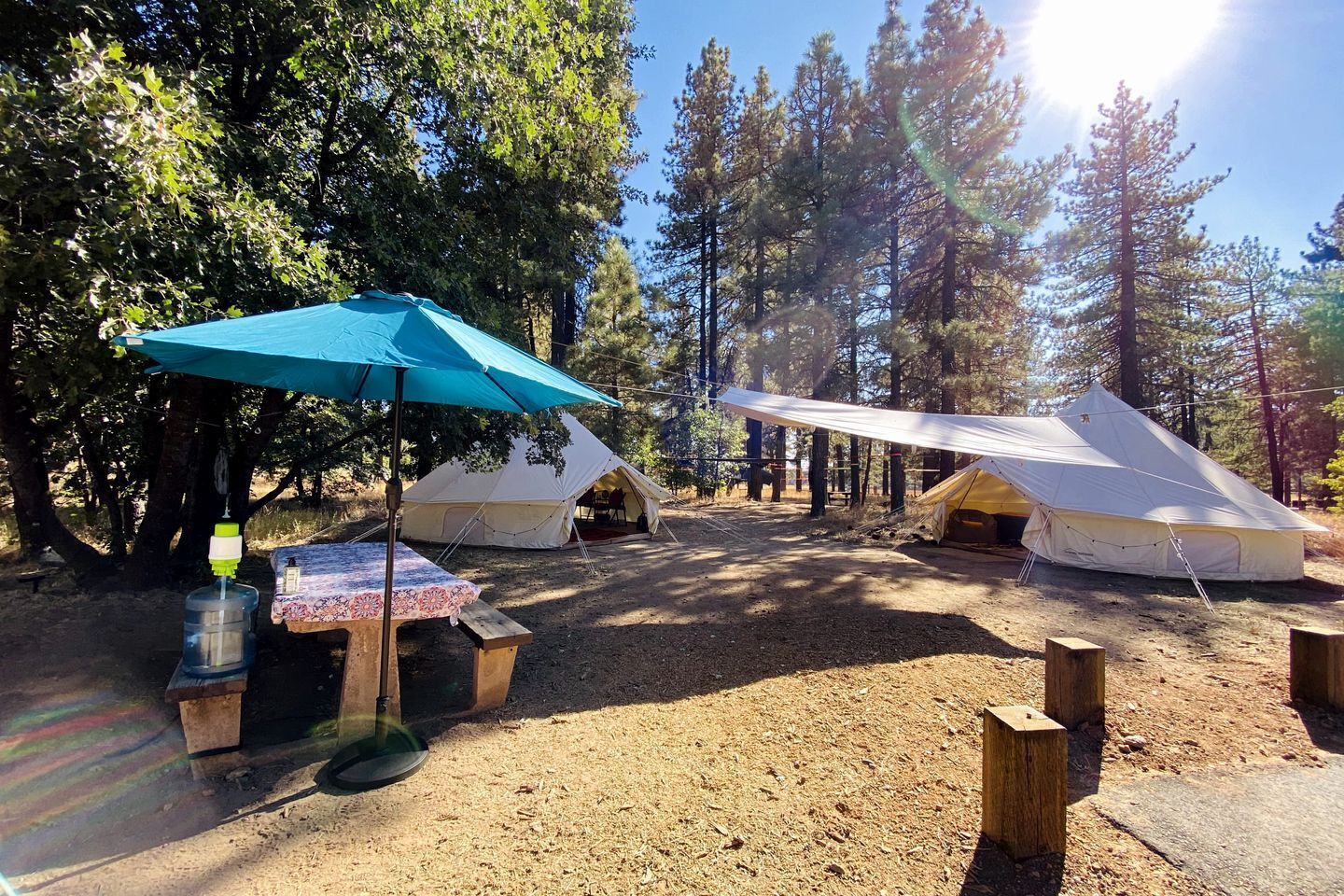 A campsite with tents, a picnic table, and a water dispenser.