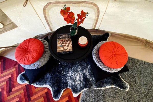A tent with a chessboard, a book, and two red cushions.