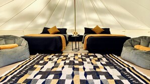 A tent-style room with two beds, a patterned rug, and two bean bag chairs.