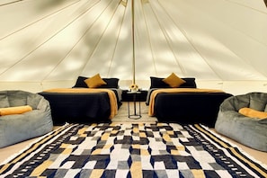 A tent-style room with two beds, a patterned rug, and two bean bag chairs.