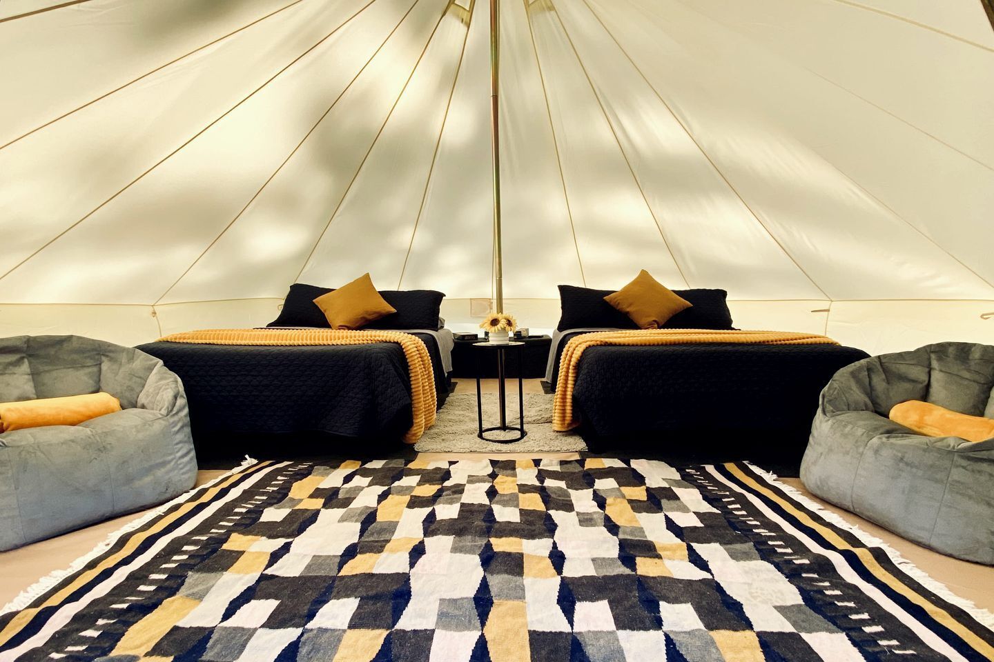 A tent-style room with two beds, a patterned rug, and two bean bag chairs.