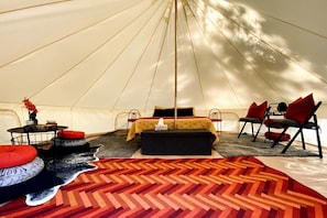 A tent interior with a bed, seating area, and a table with a vase. - Grand Adventures in Nature: Big Group-Friendly and Original Glamping in California (Mount Laguna)