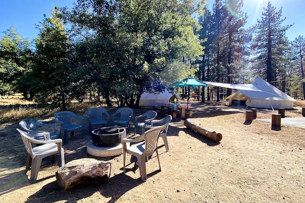 Un camping con mobiliario exterior, una parrilla y tiendas de campaña.