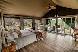 A spacious bedroom with a large bed, a ceiling fan, and a view of the outdoors through large sliding doors.