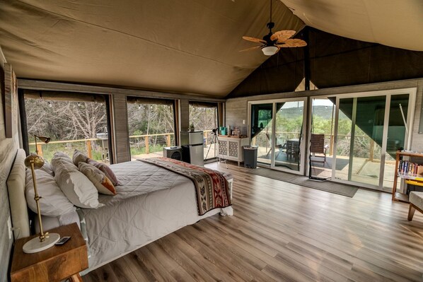 Un dormitorio amplio con una cama grande, un ventilador de techo y vistas al exterior a través de grandes puertas correderas.
